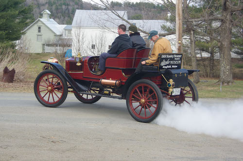 Members riding in a Stanley Steamer